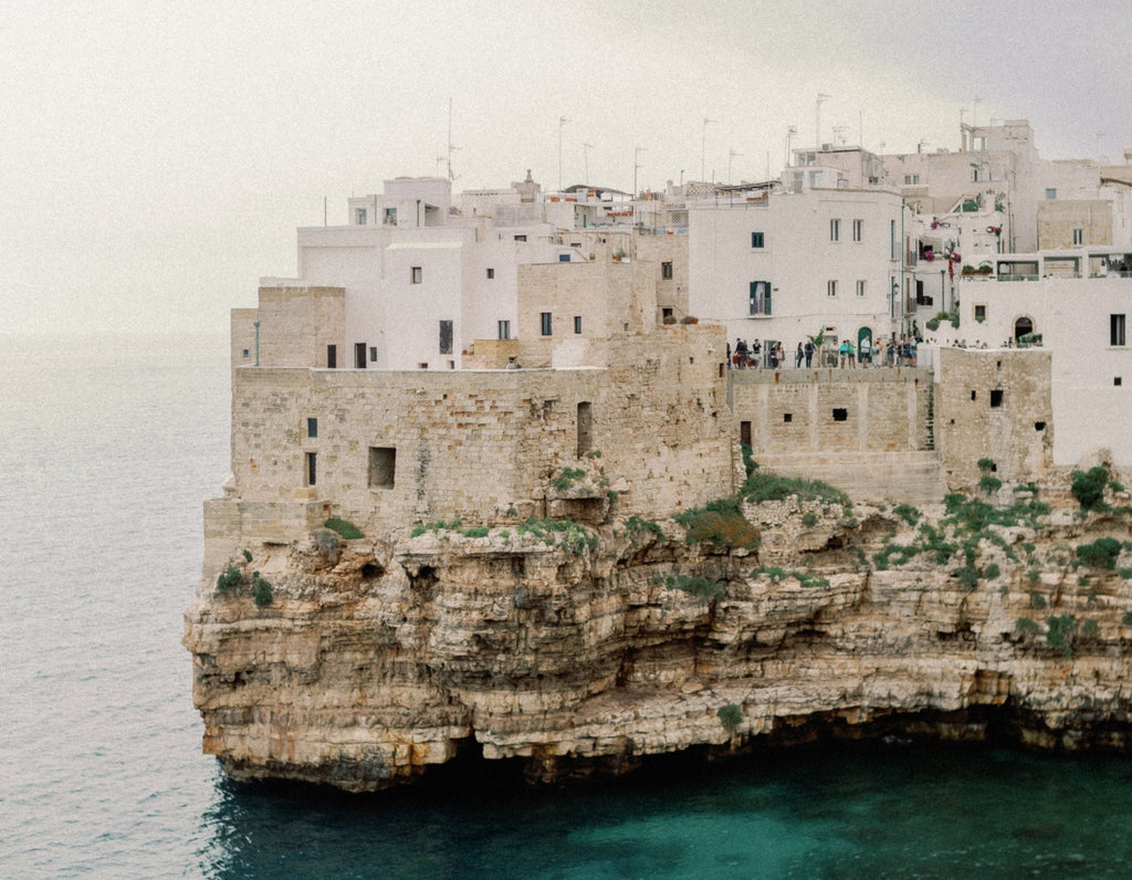 The white houses of Polignano a Mare built on top of limestone cliffs above a calm turquoise sea